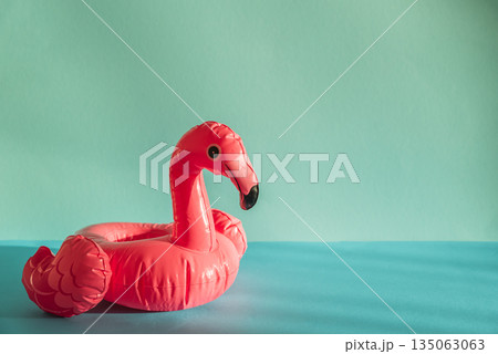 Pink Flamingo Shaped Pool Float on Turquoise Water under Sunlight. Front view 135063063