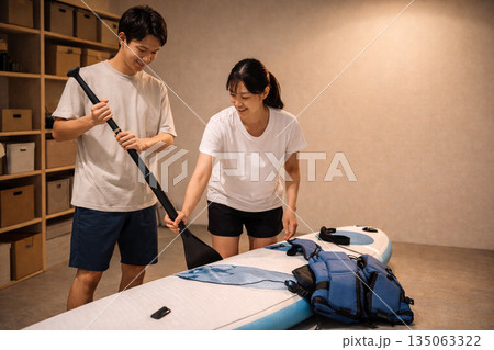 夜の室内でSUPの準備をする日本人カップル 135063322