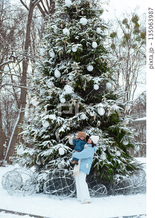Winter Family Bonding by Snowy Christmas Tree Winter Family Bonding by Snowy Christmas Tree 135063987