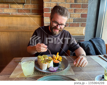 Man enjoying lunch in a restaurant by the window. Warm atmosphere, everyday pleasure and authentic moment of happiness and taste. Man enjoying lunch in a restaurant by the window. Warm atmosphere, everyday pleasure and authentic moment of happiness and taste. 135064209
