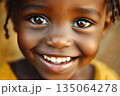 Smiling child with bright eyes and joyful expression in warm natural setting during daytime 135064278