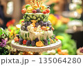 Elegant multi-tiered cake adorned with fresh fruits and intricate decorations at a festive celebration 135064280
