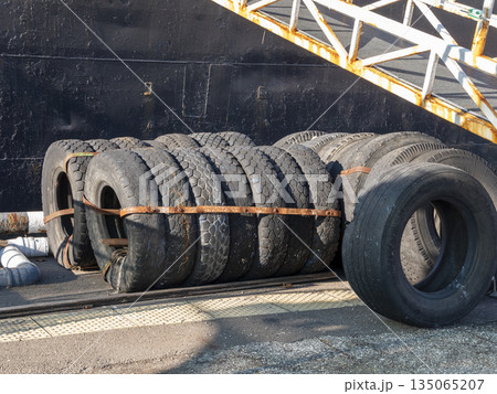 Pile of automobile wheels stacked outdoors. Used car tires and rims in an industrial or storage setting Pile of automobile wheels stacked outdoors. Used car tires and rims in an industrial or storage setting 135065207