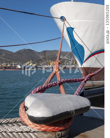 Mooring rope tied to a pier on the shore. Ship rope fastened to the dock in a mushroom shape 135065208