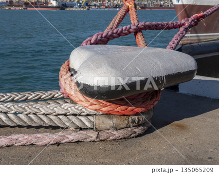 Mooring rope tied to a pier on the shore. Ship rope fastened to the dock in a mushroom shape 135065209
