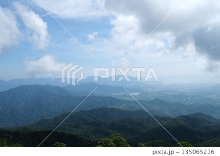 A breathtaking view of a majestic mountain range, with a few scattered clouds in the sky A breathtaking view of a majestic mountain range, with a few scattered clouds in the sky 135065216
