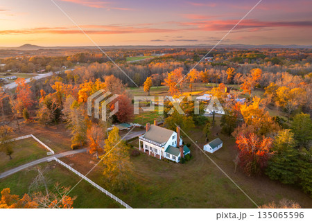 Large country homes surrounded by golden autumn woods, warm sunlight highlighting the rustic charm of rural living in the southern landscape. 135065596