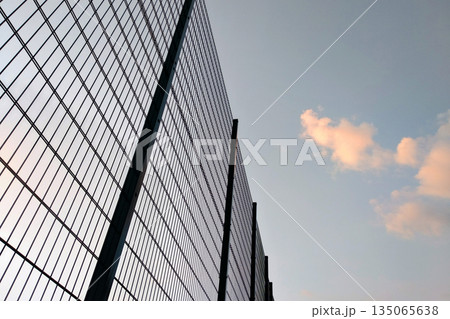 High wire mesh fence in restricted area on blue sky background. High wire mesh fence in restricted area on blue sky background. 135065638