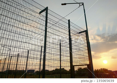 High wire mesh fence in restricted area on blue sky background. High wire mesh fence in restricted area on blue sky background. 135065639
