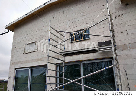 Facade of building made from white blocks with big windows under construction works. 135065716