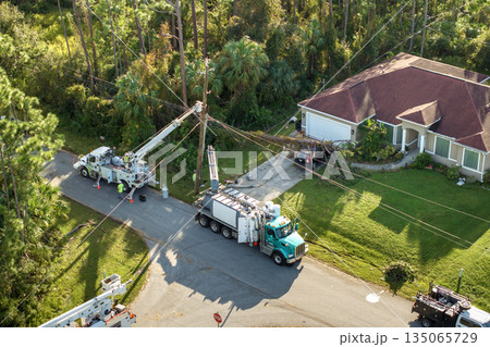 Electrician workers fixing power lines after outage. Repair of damaged electrical wires after hurricane in Florida suburban area 135065729