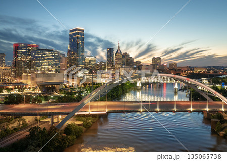 Downtown district of Nashville city in Tennessee, USA at sunset. Cars drive on Korean Veterans Memorial Bridge over Cumberland river. American travel destination. Downtown district of Nashville city in Tennessee, USA at sunset. Cars drive on Korean Veterans Memorial Bridge over Cumberland river. American travel destination. 135065738