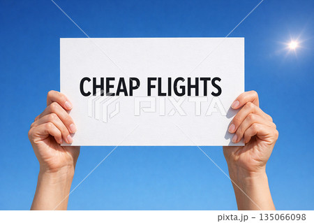 Hands holding a white paper sign that reads cheap flights against bright blue sky 135066098