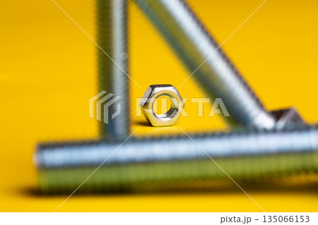 Metal Screw and Bolt Isolated on Vibrant Yellow Background: Construction and Engineering Essentials 135066153