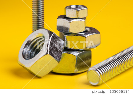 Metal Screw and Bolt Isolated on Vibrant Yellow Background: Construction and Engineering Essentials Metal Screw and Bolt Isolated on Vibrant Yellow Background: Construction and Engineering Essentials 135066154