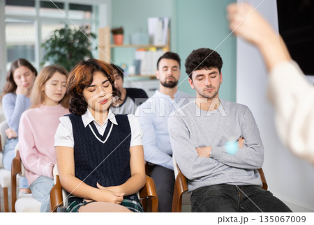 Students sit with their eyes closed, meditation 135067009