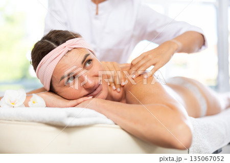 Female masseur works out shoulder and back problem area for female athlete client. Close-up Female masseur works out shoulder and back problem area for female athlete client. Close-up 135067052
