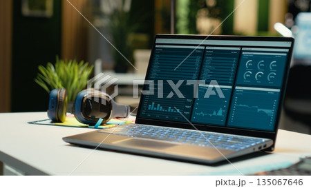 Modern laptop showcasing data reports in an empty office late at night, performance metrics and forecasting graphs. Corporate workspace equipped with technology to reflect business management. 135067646