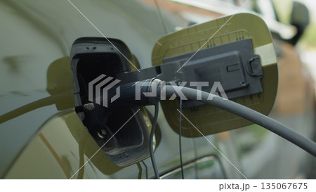 Closeup of zero emission EV vehicle connected to charging dock, emphasizing commitment to cleaner environment. Electric car plugged into power supply, part of global push for decarbonizing transport 135067675