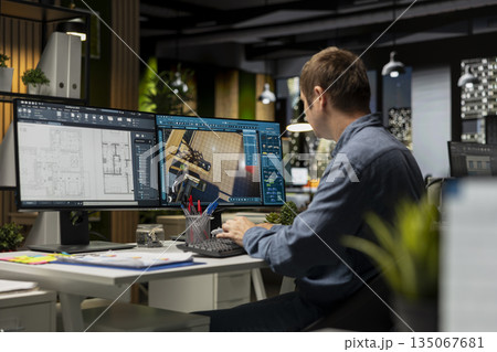 Male employee creates 3D render of an apartment interior using blueprints and architectural software. Using computer aided tools and models to allow customization of flooring and layout. 135067681
