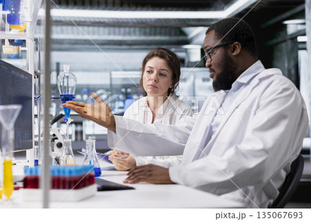 Team of lab scientists working together on PC, evaluating genetic markers associated with disease risk. Teamworking colleagues study DNA strand mapping with genomics analysis program on computer 135067693