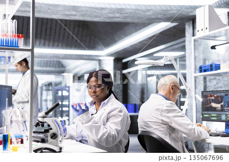 African american researcher examining Petri dish in a biolab. Observation of matter, microorganisms and cellular growth reflects experimental science and pathology investigation. African american researcher examining Petri dish in a biolab. Observation of matter, microorganisms and cellular growth reflects experimental science and pathology investigation. 135067696