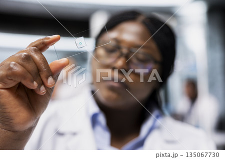 Close up of nanotechnology researcher analyzing bacterial culture slide to test antibiotic efficacy. Lab employee at work holding glass sample up to inspect reaction results for new drug development Close up of nanotechnology researcher analyzing bacterial culture slide to test antibiotic efficacy. Lab employee at work holding glass sample up to inspect reaction results for new drug development 135067730
