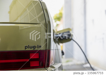 Close up of plug in electric vehicle charging, connected to electric cable. Power connector plugged into EV car, concept of shift toward sustainable mobility and renewable energy transportation 135067733