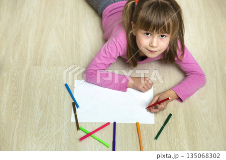 Cute child girl drawing with colorful pencils crayons on white paper. Art education, creativity concept. 135068302