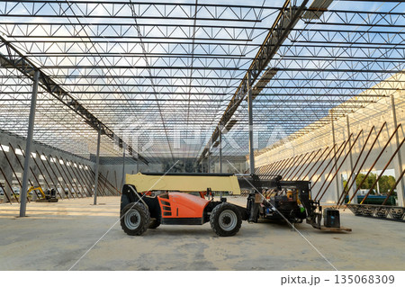 Construction site of logistic center with assembling of concrete and metal frame walls. Aerial view of large development area of commercial structure Construction site of logistic center with assembling of concrete and metal frame walls. Aerial view of large development area of commercial structure 135068309