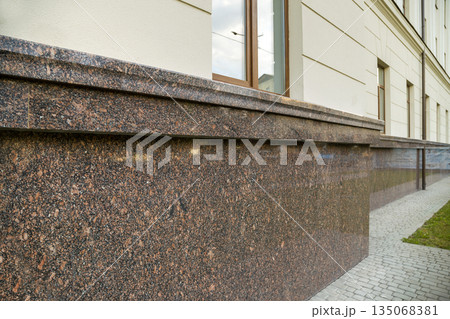 Close up view of part of a building facade with the surface of granite wall. Natural stone materials. Close up view of part of a building facade with the surface of granite wall. Natural stone materials. 135068381