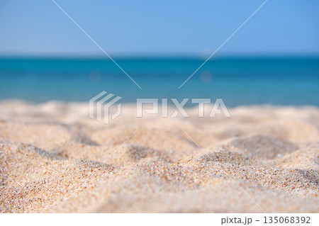 Close up of clean yellow sand surface covering seaside beach with blue sea water on background. Travel and vacations concept. 135068392