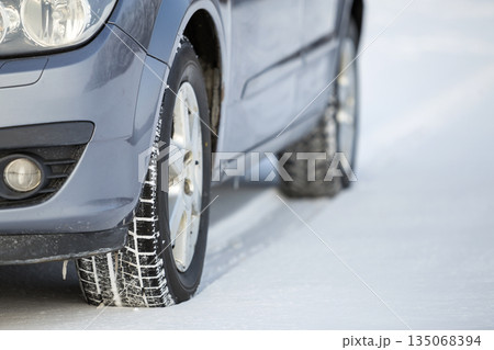 Close up of a car tire parked on snowy road on winter day. Transportation and safety concept. Close up of a car tire parked on snowy road on winter day. Transportation and safety concept. 135068394