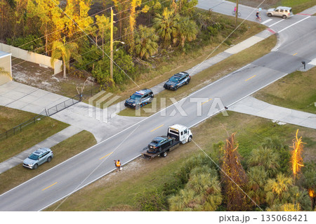 Car crash with tow truck hauling damaged car and first responders helping at accident site on American street. Vehicle collision on road in USA Car crash with tow truck hauling damaged car and first responders helping at accident site on American street. Vehicle collision on road in USA 135068421