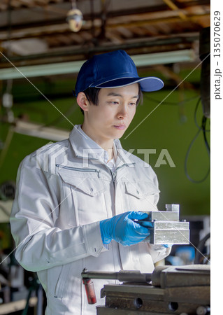 工場のプレス機で作業する若い男性 135070629