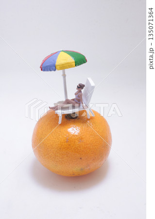 Whimsical Orange Beach Scene With Miniature Figure Relaxing 135071364