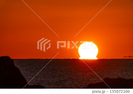 水平線に沈む夕日 135072100