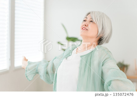 家のリビングで深呼吸するグレイヘアのシニア女性 家のリビングで深呼吸するグレイヘアのシニア女性 135072476