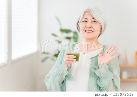 健康のため青汁・グリーンスムージー・野菜ジュースを飲むシニア女性 135072518
