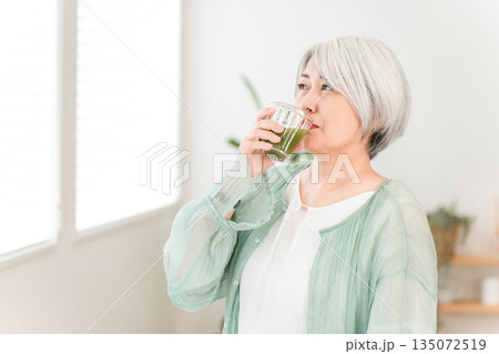 健康のため青汁・グリーンスムージー・野菜ジュースを飲むシニア女性 135072519