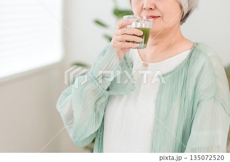健康のため青汁・グリーンスムージー・野菜ジュースを飲むシニア女性 135072520