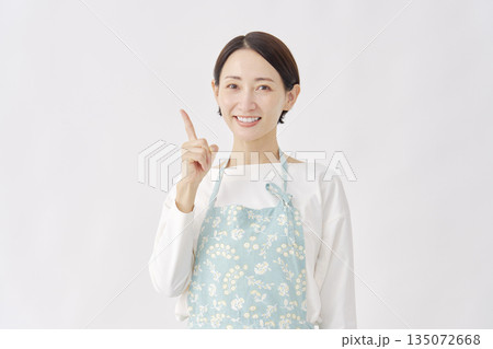 左を指差すエプロンを着た女性 白背景 左を指差すエプロンを着た女性 白背景 135072668