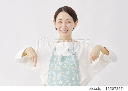 下を指差すエプロンをつけた女性 白背景 下を指差すエプロンをつけた女性 白背景 135072674