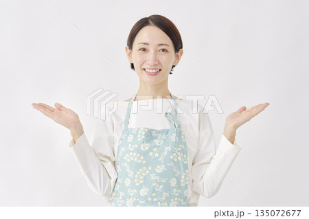 左右を手のひらで指すエプロンをつけた女性 白背景 左右を手のひらで指すエプロンをつけた女性 白背景 135072677