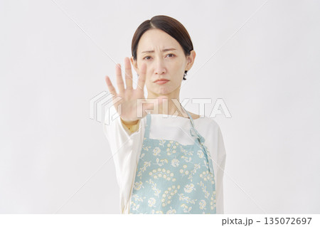 エプロンをつけた女性 ストップのジェスチャー 白背景 エプロンをつけた女性 ストップのジェスチャー 白背景 135072697