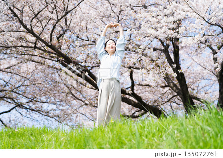 桜の木の下でストレッチをする若い女性　ライフスタイルイメージ 135072761
