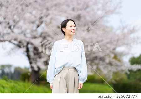 桜の木の前でポージングする若い女性　ライフスタイルイメージ 135072777