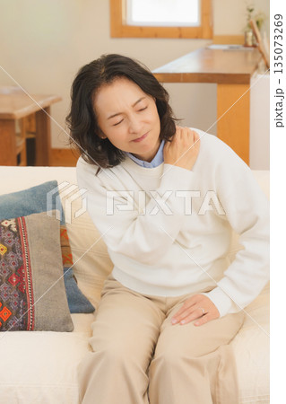 リビングでソファに座り肩をもむミドル女性 135073269