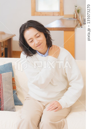 リビングでソファに座り肩をもむミドル女性 リビングでソファに座り肩をもむミドル女性 135073270