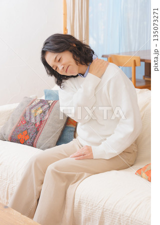 リビングでソファに座り肩をもむミドル女性 135073271